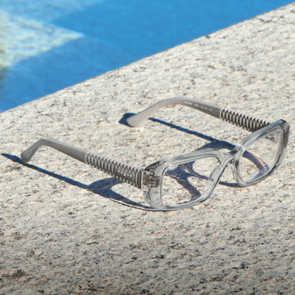 Lunettes de vue Vogue avec une monture transparente posées près d'une piscine