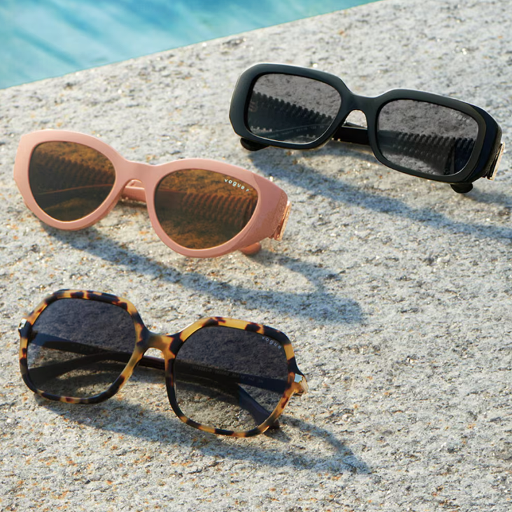 Trois paires de lunettes de soleil Vogue posées sur une surface près d'une piscine