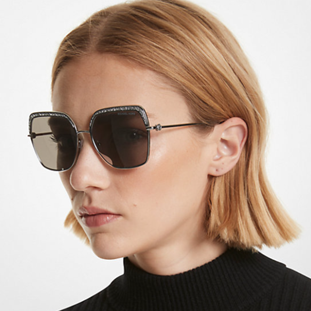 Femme portant des lunettes de soleil Michael Kors avec une monture métallique et des verres foncés