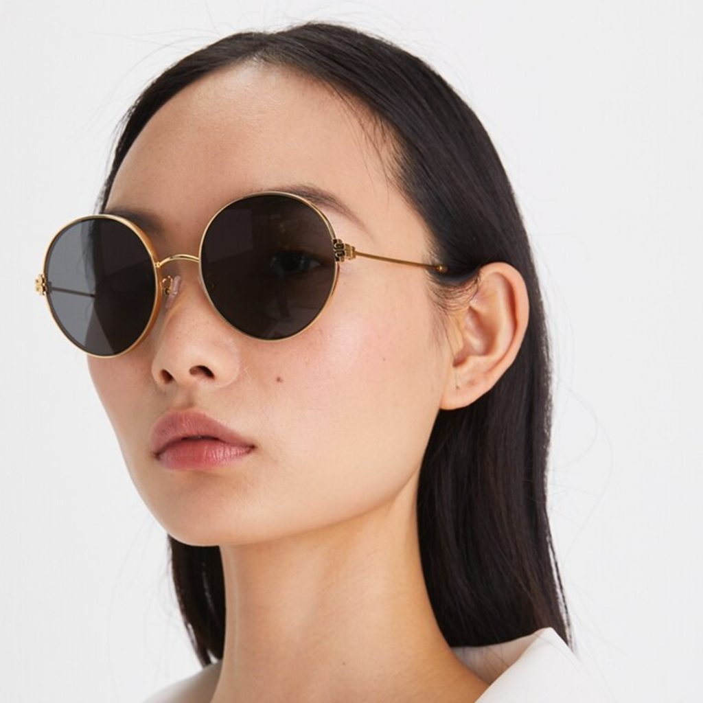 Femme portant des lunettes de soleil rondes Tory Burch avec une monture dorée