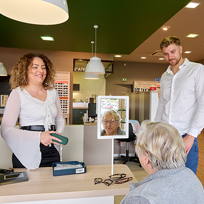 Opticiens de Luneo Opticiens aidant une cliente âgée à choisir des montures