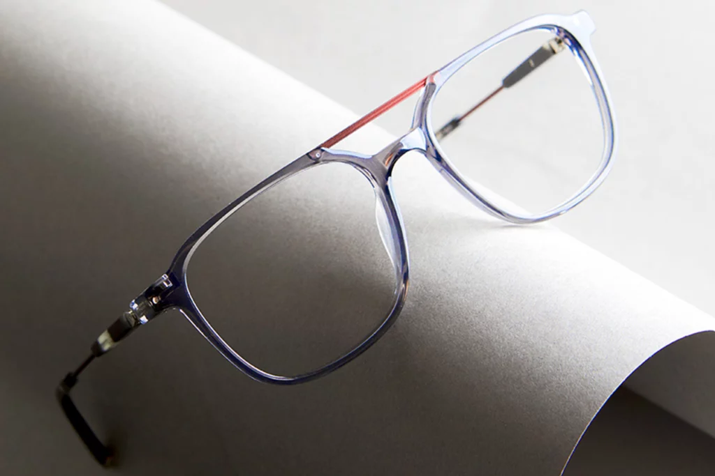 Paire de lunettes Aspex avec une monture transparente posée sur un rouleau de papier