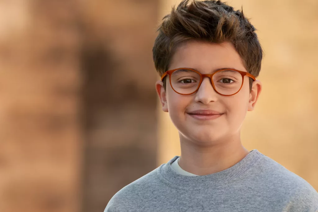 Jeune garçon souriant portant des lunettes orange chez Luneo Opticiens